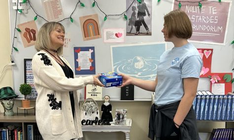 Sophomore Mackenzie Bolton gives a box of tampons to TIE Club representative, Melanie Gross, to help end period poverty. The tampons will be donated locally to those in need.