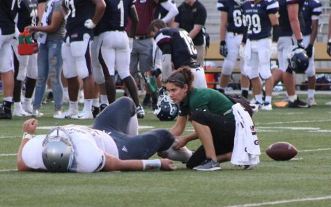 Athletic trainer Rebecca Townsend helps an injured player on the field during the Southwest vs. Southeast game.