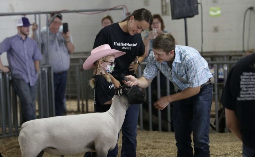 A showman and her buddy show their lamb to the judge.