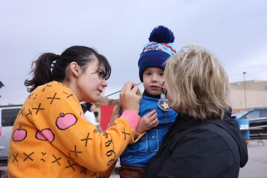 Senior Milana Sherman paints a childs face at Trunk-or-Treat. On Thursday, Oct. 27, Student Council hosted Trunk-or-Treat in the Lincoln Southwest parking lot from 5:00-7:30 p.m.