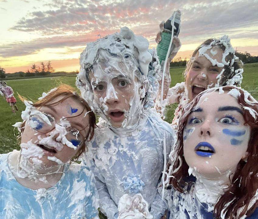 Juniors Katie Timmer, Jack McCormick, Charlie Rader (left to right) and senior Allison Ernst (background) pose for a photo after a shaving cream battle between seniors and juniors/sophomores. This was their resolution to the beginning of the Rez Prank Wars. 
