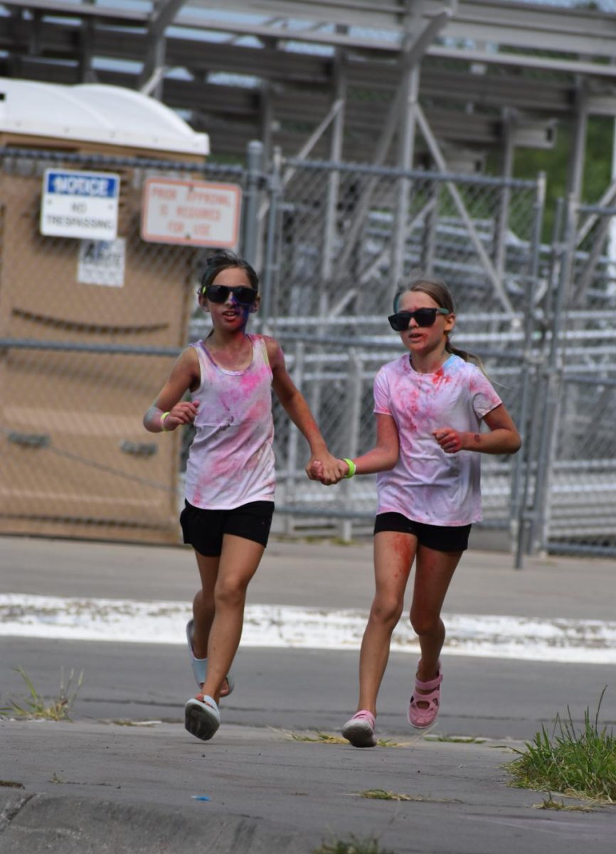 Two young girls run hand and hand at the 2023-2024 StuCo Color Run. Starting at 10 a.m. on Saturday, Aug. 24, Student Council (StuCo) will present the Color Run, a two lap run around Southwest High School where chalk powder is thrown at individuals throughout different parts of the course.