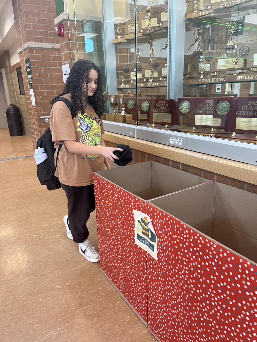 Freshman Mariam Baker donating a hat to Winters Items Drive drop of bin. This event is going on through all of January and is being donated to the Peoples City Mission in February.