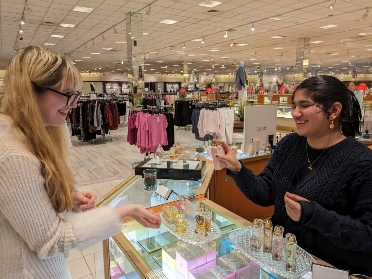 Senior Samara Tuma assists a customer with a purchase at Von Maur. Many workers like her received a wage increase at the new year. 