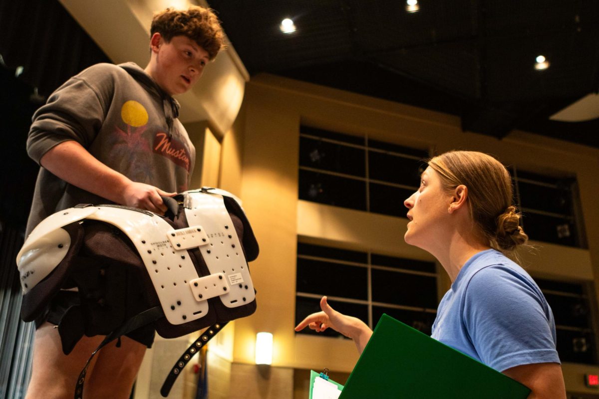 Mrs. Brandi Benson (right) speaks with junior Grant Johnson (left) during a rehearsal for "H2$ in Business."  Benson is the new assistant director for the 2024-25 school year.