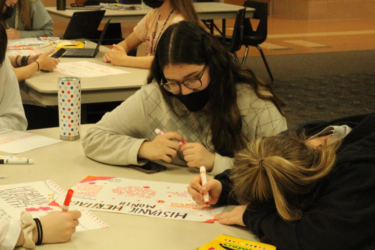 Two students working on posters in TIE Club. TIE Club makes posters and does other activities to influence equity around the school.