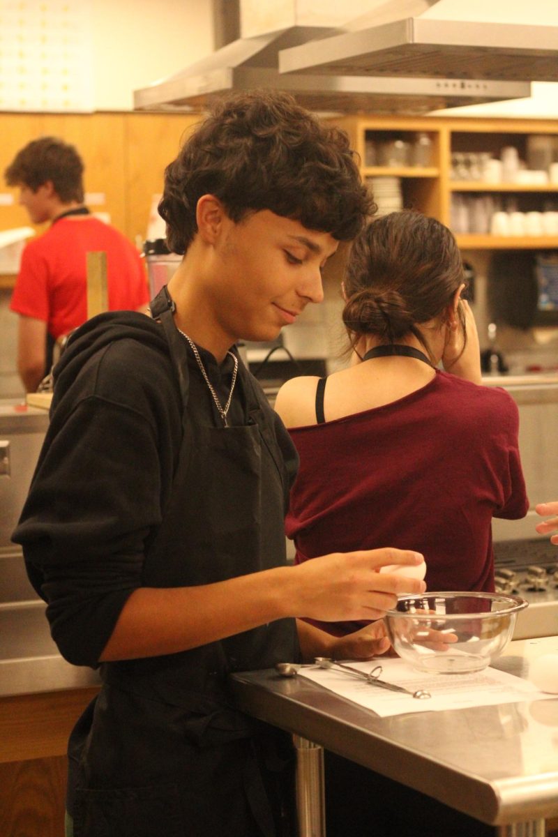 Sophomore Zane Vergil cracks an egg into a bowl in Culinary class. The class was making omelettes. 
